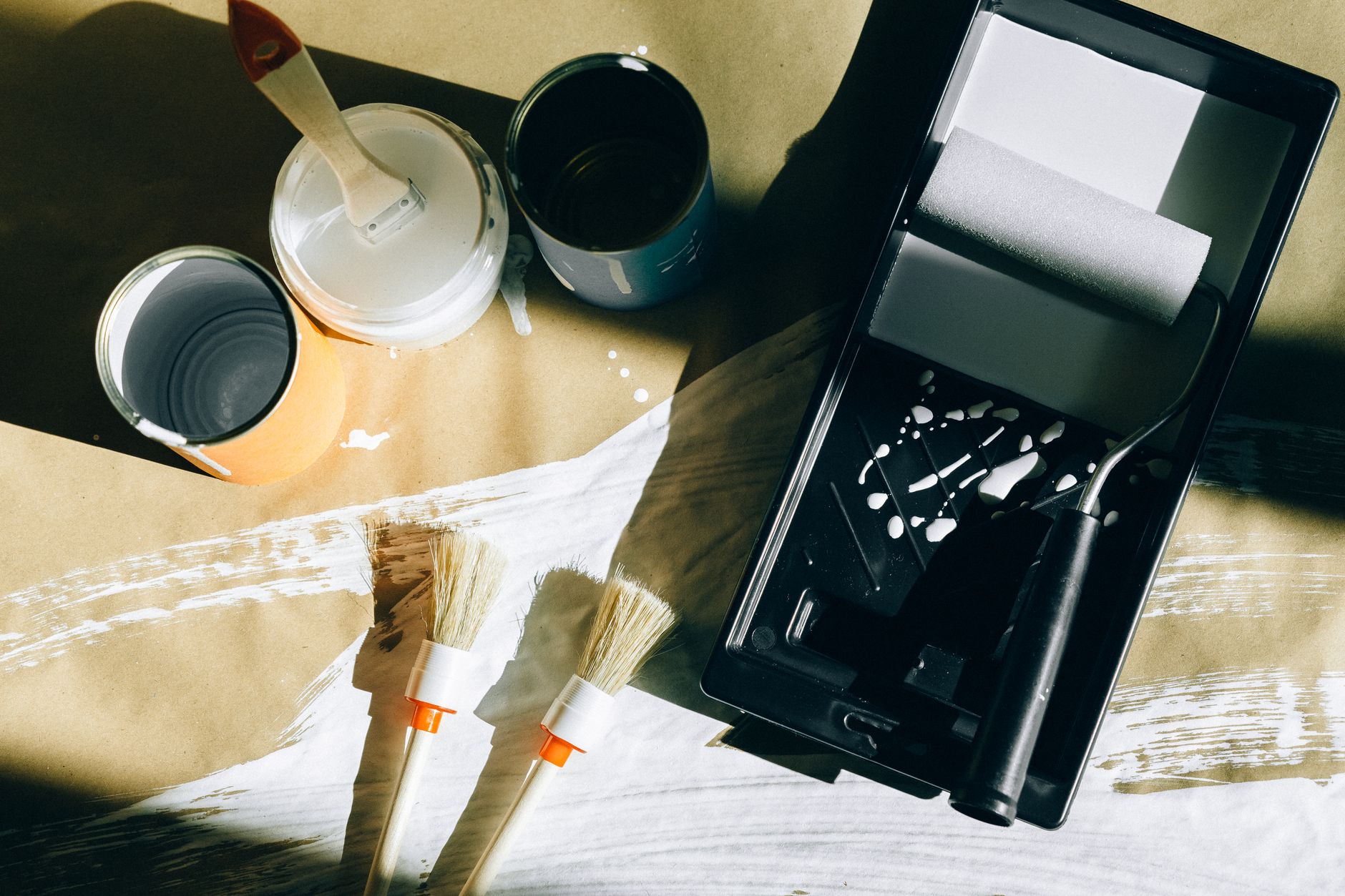 Top view of painting tools including brushes, rollers, and paint cans on paper in Pasadena, CA
